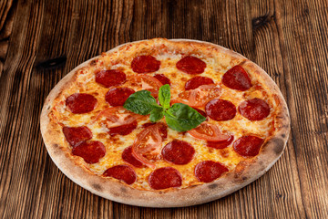 Hot pepperoni pizza with spicy sausage and melted cheese on wooden table