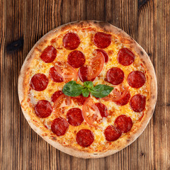 Hot pepperoni pizza with spicy sausage and melted cheese on wooden table