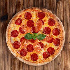 Hot pepperoni pizza with spicy sausage and melted cheese on wooden table