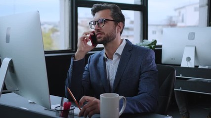 Office manager talking on smartphone with business partner or customer consulting phone call conversation sitting by computer in company workspace. - Powered by Adobe