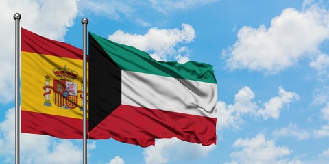 Spain and Kuwait flag waving in the wind against white cloudy blue sky together. Diplomacy concept, international relations.