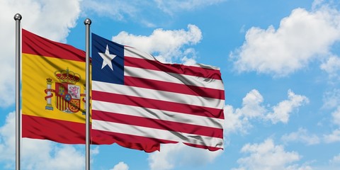 Spain and Liberia flag waving in the wind against white cloudy blue sky together. Diplomacy concept, international relations.