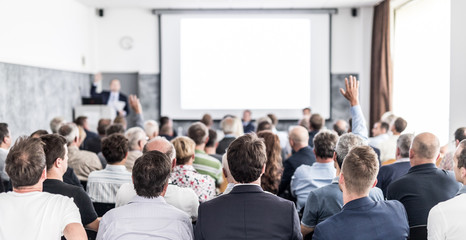 I have a question. Group of business people sitting at the chairs in conference hall. Businessman...