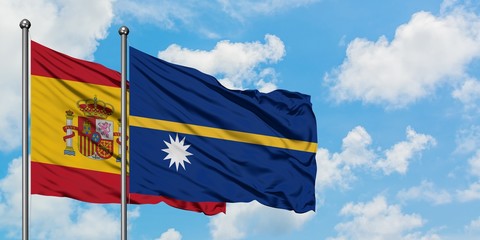 Spain and Nauru flag waving in the wind against white cloudy blue sky together. Diplomacy concept, international relations.