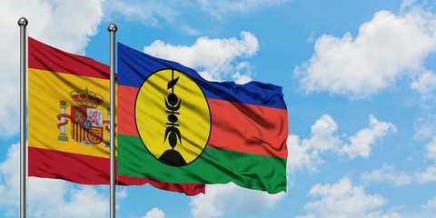Spain and New Caledonia flag waving in the wind against white cloudy blue sky together. Diplomacy concept, international relations.