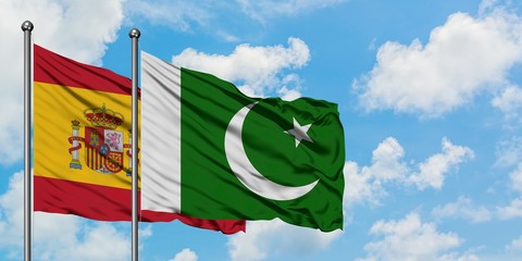 Spain and Pakistan flag waving in the wind against white cloudy blue sky together. Diplomacy concept, international relations.