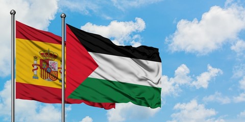 Spain and Palestine flag waving in the wind against white cloudy blue sky together. Diplomacy concept, international relations.