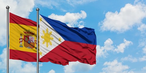 Spain and Philippines flag waving in the wind against white cloudy blue sky together. Diplomacy concept, international relations.