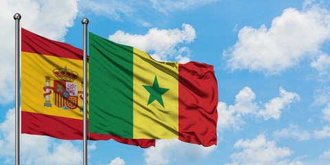 Spain and Senegal flag waving in the wind against white cloudy blue sky together. Diplomacy concept, international relations.