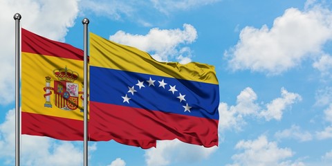 Spain and Venezuela flag waving in the wind against white cloudy blue sky together. Diplomacy concept, international relations.