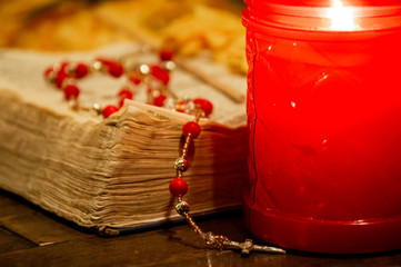 Worn pages of an open Bible book and a rosary beads.