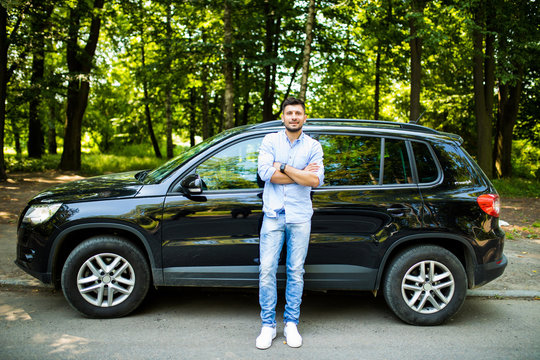 Successful young man standing near car outdoors