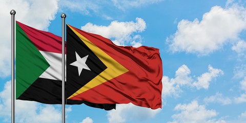 Sudan and East Timor flag waving in the wind against white cloudy blue sky together. Diplomacy concept, international relations.