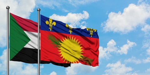 Sudan and Guadeloupe flag waving in the wind against white cloudy blue sky together. Diplomacy concept, international relations.