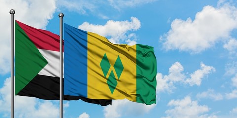 Sudan and Saint Vincent And The Grenadines flag waving in the wind against white cloudy blue sky together. Diplomacy concept, international relations.