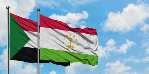 Sudan and Tajikistan flag waving in the wind against white cloudy blue sky together. Diplomacy concept, international relations.
