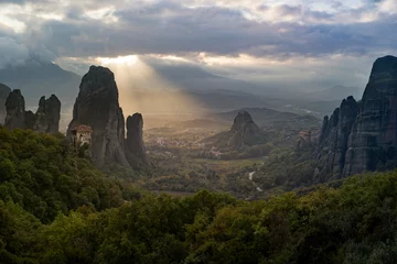 Selbstklebende Fototapeten Beautiful god ray sunbeam illuminating Meteora's Roussanou convent during sunset © Marcel