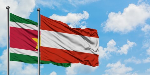 Suriname and Austria flag waving in the wind against white cloudy blue sky together. Diplomacy concept, international relations.