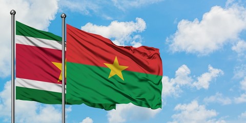 Suriname and Burkina Faso flag waving in the wind against white cloudy blue sky together. Diplomacy concept, international relations.