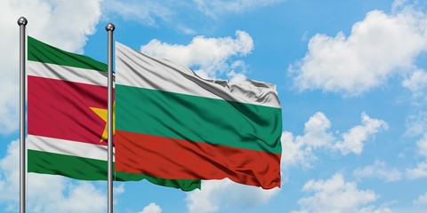 Suriname and Bulgaria flag waving in the wind against white cloudy blue sky together. Diplomacy...
