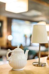 Lonely lantern and white teapot on shelf in cafe. Decor of restaurant natural materials