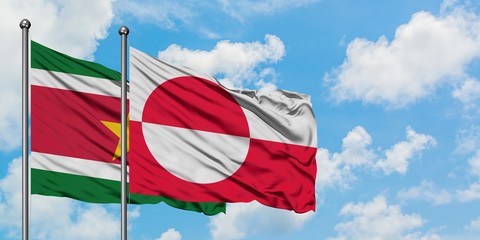 Suriname and Greenland flag waving in the wind against white cloudy blue sky together. Diplomacy concept, international relations.