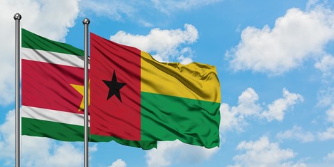 Suriname and Guinea Bissau flag waving in the wind against white cloudy blue sky together. Diplomacy concept, international relations.