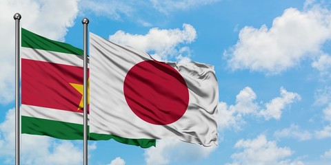 Suriname and Japan flag waving in the wind against white cloudy blue sky together. Diplomacy concept, international relations.