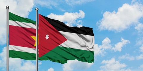 Naklejka na ściany i meble Suriname and Jordan flag waving in the wind against white cloudy blue sky together. Diplomacy concept, international relations.