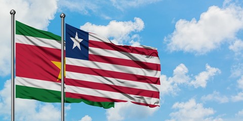 Suriname and Liberia flag waving in the wind against white cloudy blue sky together. Diplomacy concept, international relations.