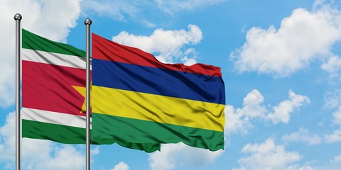 Suriname and Mauritius flag waving in the wind against white cloudy blue sky together. Diplomacy concept, international relations.