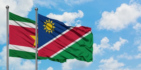 Suriname and Namibia flag waving in the wind against white cloudy blue sky together. Diplomacy concept, international relations.
