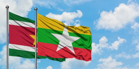 Suriname and Myanmar flag waving in the wind against white cloudy blue sky together. Diplomacy concept, international relations.