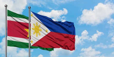 Suriname and Philippines flag waving in the wind against white cloudy blue sky together. Diplomacy concept, international relations.
