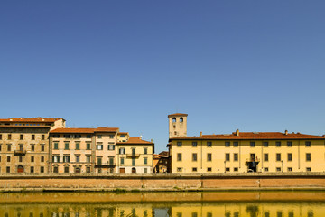 Fototapeta premium Scenic view of Lungarno Antonio Pacinotti riverside with the Torre de Cantone tower and the Royal Palace (Palazzo Reale) in a sunny summer day, Pisa, Tuscany, Italy