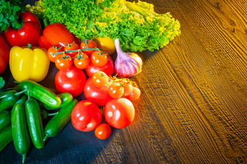 Fresh vegetables lie on a wooden surface. Vegetable still life illuminated by light. Ingredients for Greek salad. Vegetarianism. Daily consumption of vegetables. Wholesome food. Garnish. Snack.