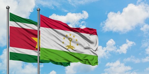 Suriname and Tajikistan flag waving in the wind against white cloudy blue sky together. Diplomacy concept, international relations.