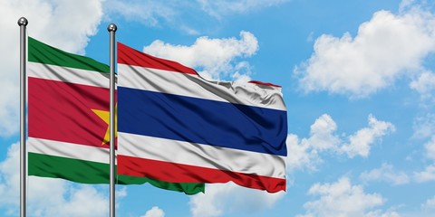 Suriname and Thailand flag waving in the wind against white cloudy blue sky together. Diplomacy concept, international relations.