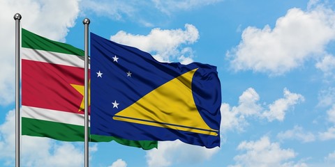 Suriname and Tokelau flag waving in the wind against white cloudy blue sky together. Diplomacy concept, international relations.