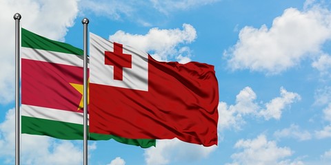 Suriname and Tonga flag waving in the wind against white cloudy blue sky together. Diplomacy concept, international relations.