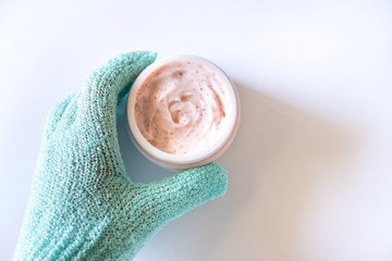 Hand in glove holding scrub jar.