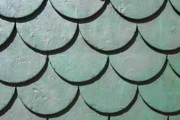 Close-up of a green carved wood door with fish scales pattern background, Italy © Simona Sirio