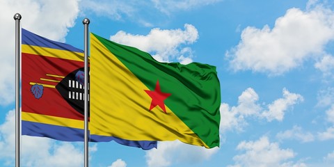 Swaziland and French Guiana flag waving in the wind against white cloudy blue sky together. Diplomacy concept, international relations.