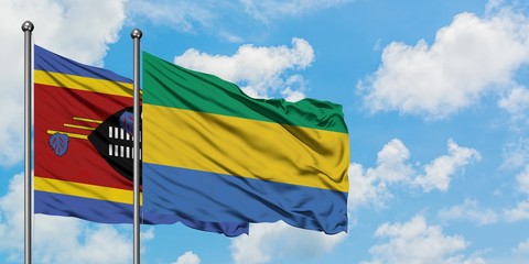Swaziland and Gabon flag waving in the wind against white cloudy blue sky together. Diplomacy...