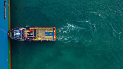 Aerial top down view of tug pilot boat assist vessel pushing large tanker to position, Keratsini, Attica, Greece - obrazy, fototapety, plakaty