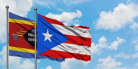 Swaziland and Puerto Rico flag waving in the wind against white cloudy blue sky together. Diplomacy concept, international relations.