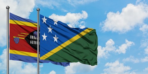 Swaziland and Solomon Islands flag waving in the wind against white cloudy blue sky together. Diplomacy concept, international relations.