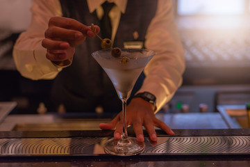 The Asian bartender poured a cocktail into a glass of beverage.