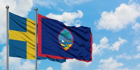 Sweden and Guam flag waving in the wind against white cloudy blue sky together. Diplomacy concept, international relations.