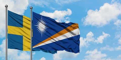 Sweden and Marshall Islands flag waving in the wind against white cloudy blue sky together....